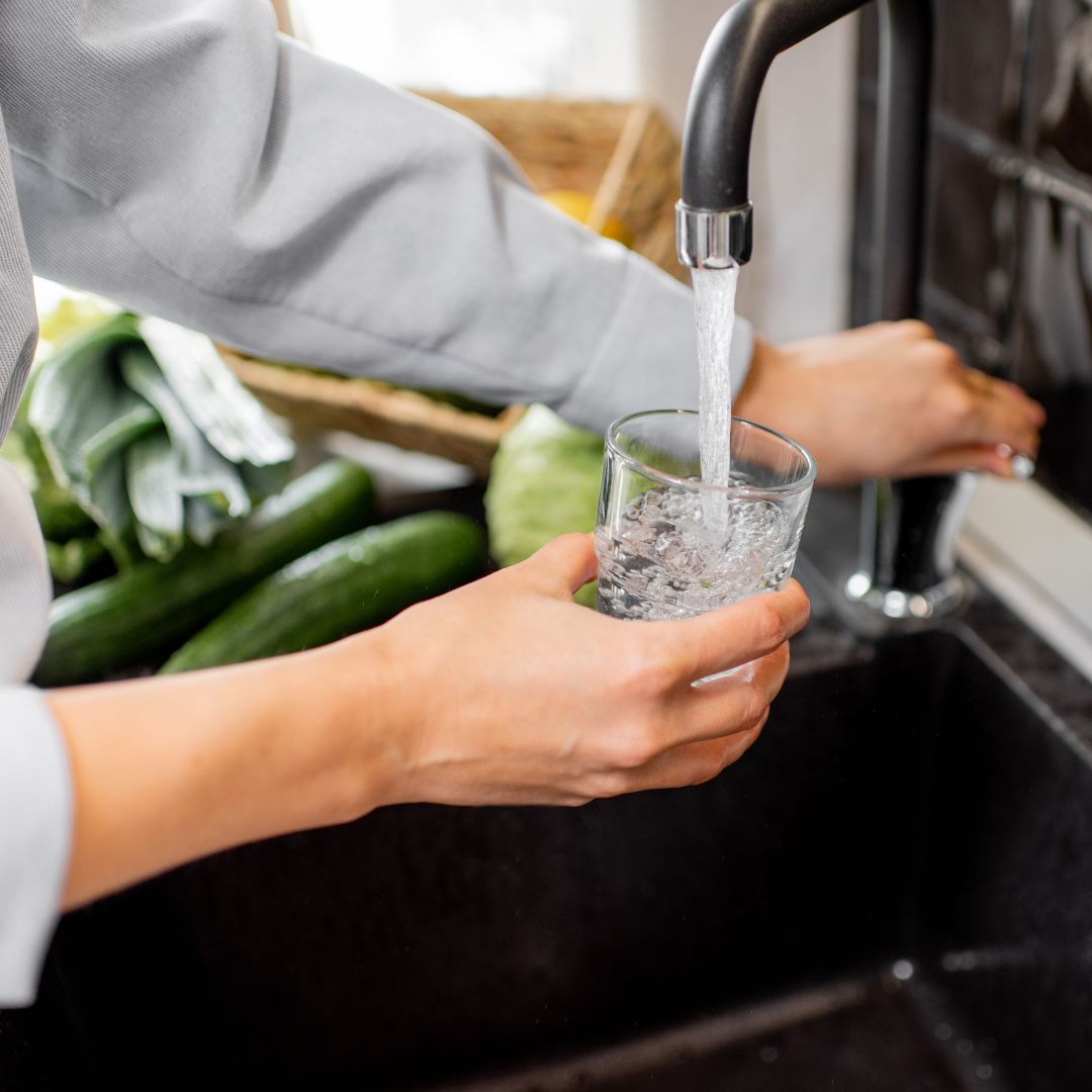 Person filling a glass with tap water