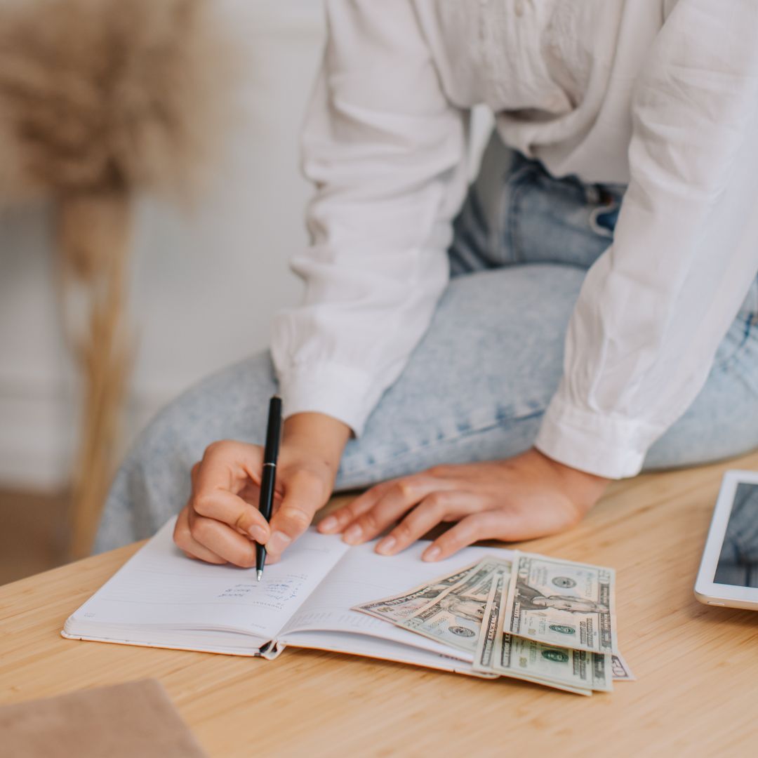 Person writing on a note pad while budgeting