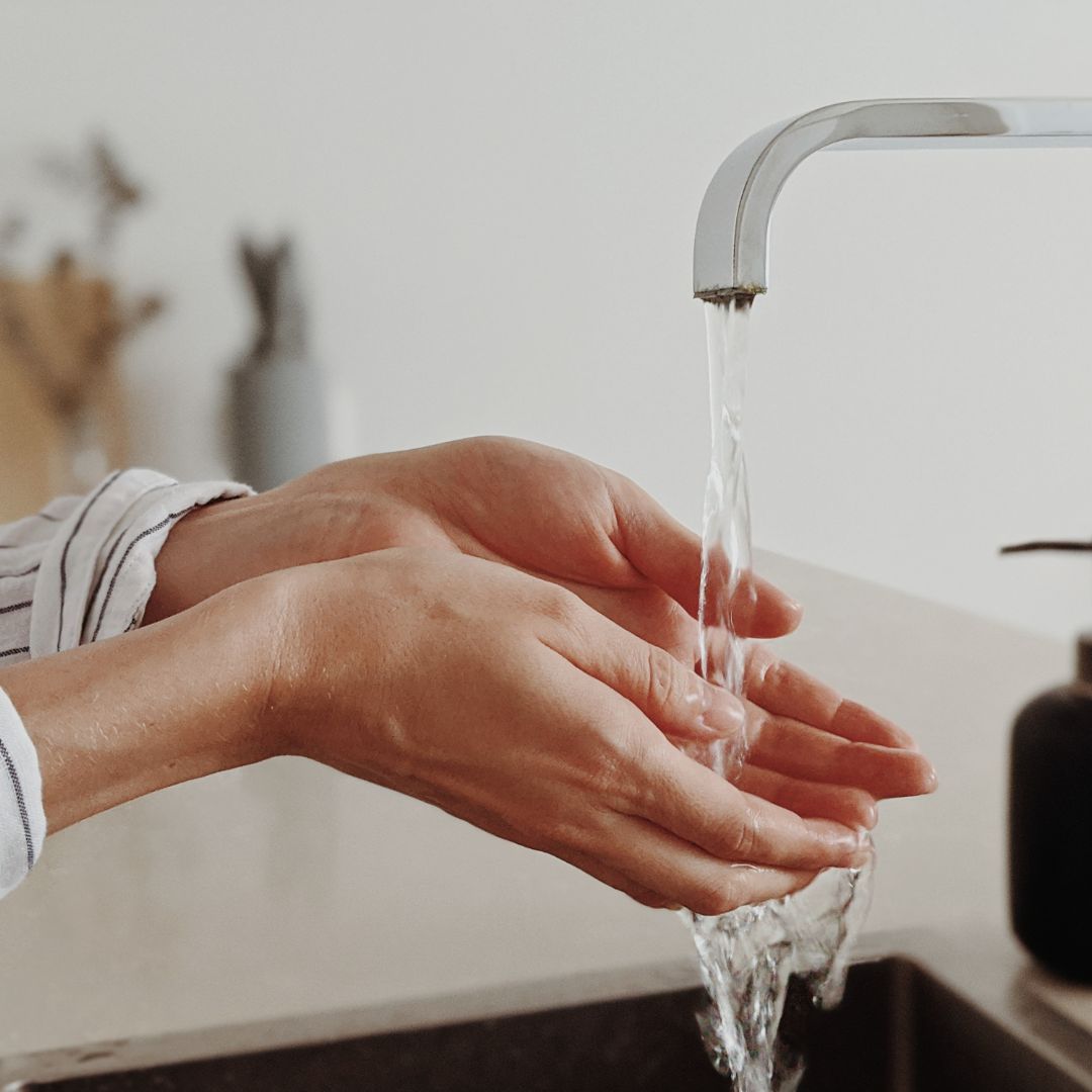 Person holding their hands under a stream of water from a faucet
