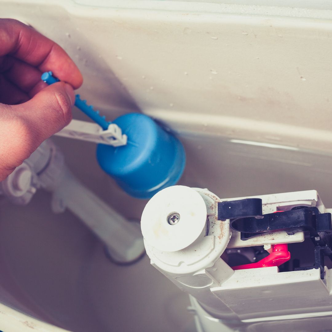 person adjusting flapper valve in toilet