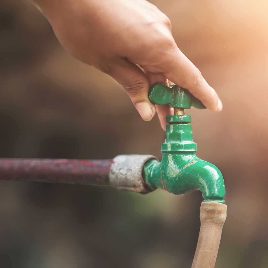 person adjusting outdoor faucet