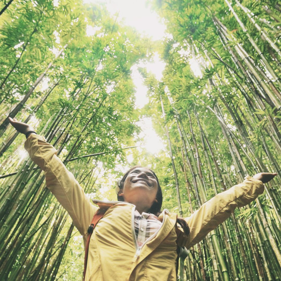 person smiling looking up a forest